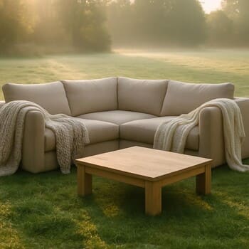 Soft corner sofa on a dewy lawn with blankets and a low coffee table