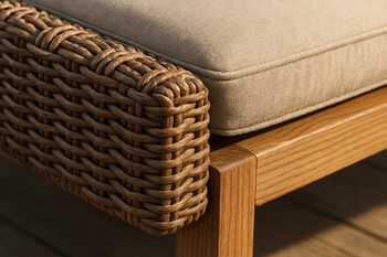 Close view of outdoor cushion, wooden armrest and grass meeting in soft light